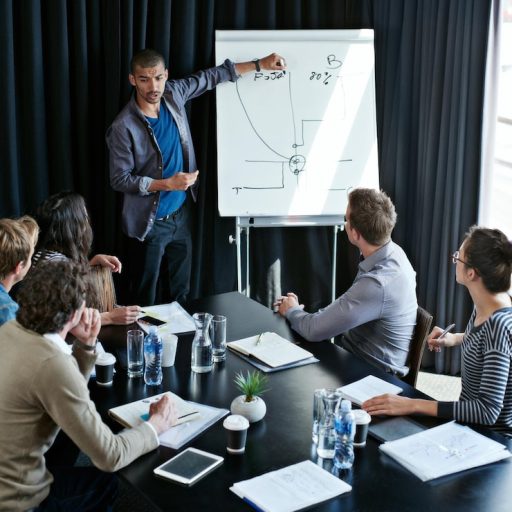 explaining-this-quarters-numbers-shot-young-man-giving-presentation-whiteboard-colleagues-sitting-around-table-boardroom_590464-6984